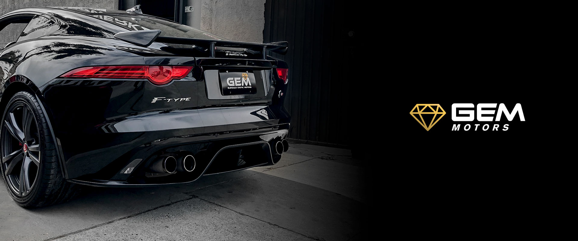 A black car parked in a garage with its rear end.